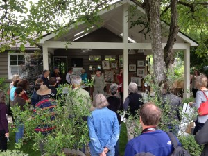 A group of people gathered under a covered patio, listening to a speaker.