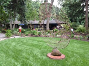 A metal sculpture, a house, and a garden with landscaping. 