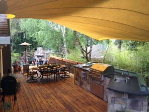 Covered deck with a dining table, grill, and kitchen area. 