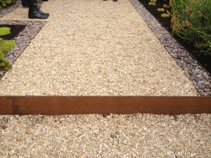 A light beige gravel path with a rusty-colored metal border.