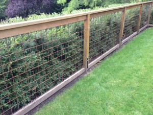 A wooden fence with wire mesh panels.