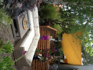 A patio with a beige sectional sofa, wooden coffee table, and people. 